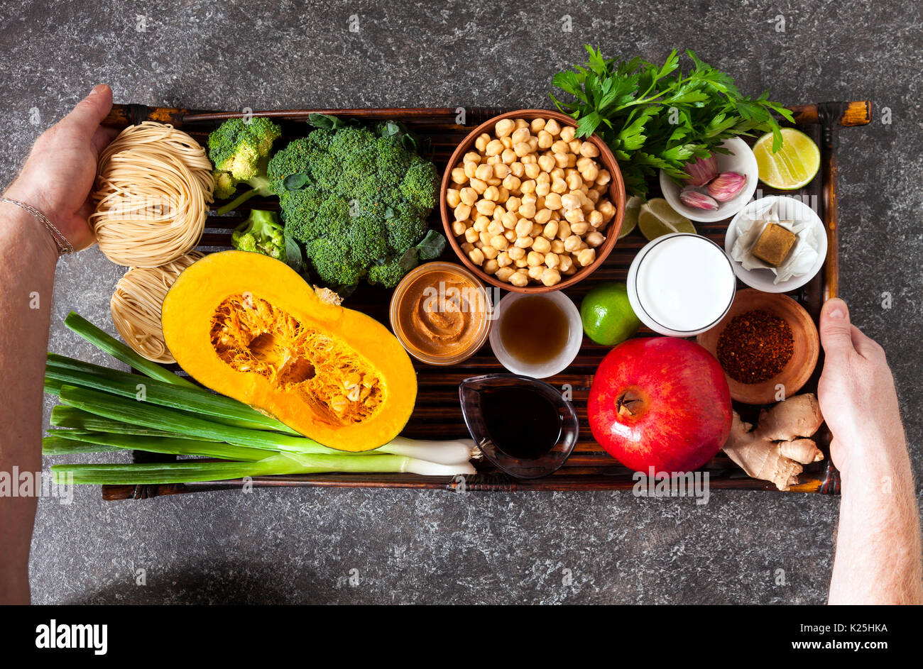 Ingredienti alimentari di cucina asiatica su un vassoio di bambù e gli uomini con le mani in mano che lo tengono Foto Stock