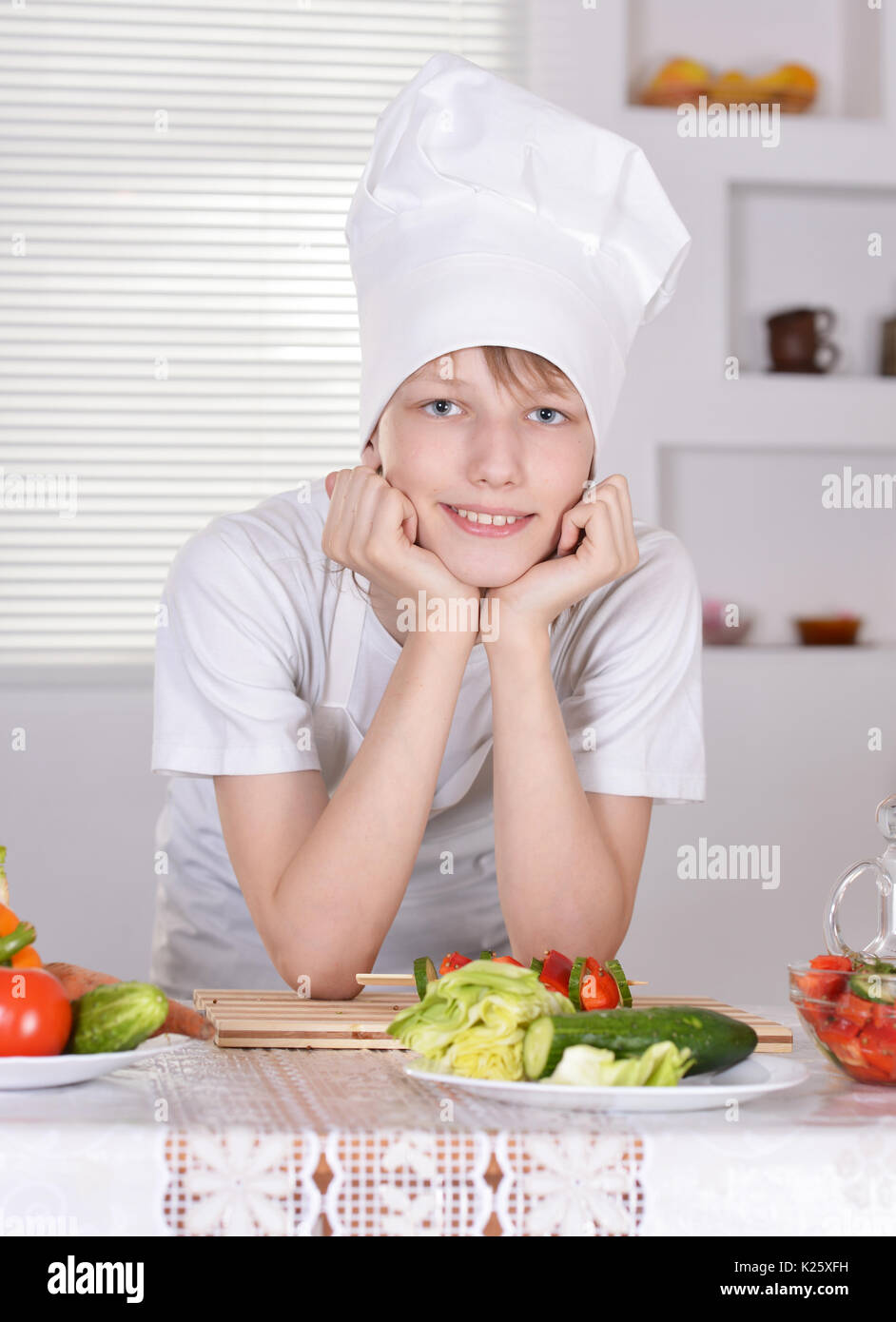 Teen boy in chef hat in posa in cucina Foto Stock