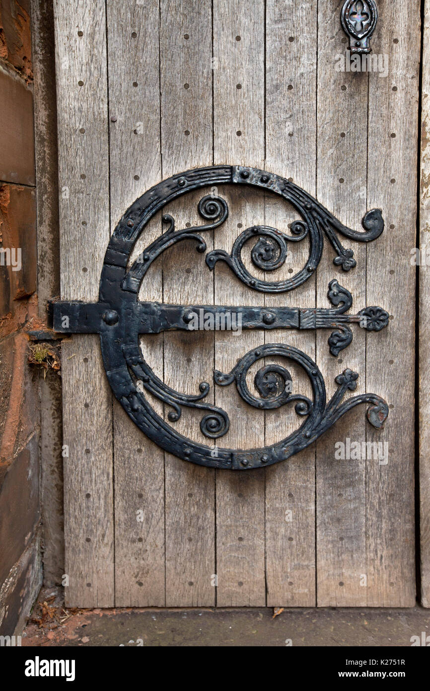 Grandi e decorati cardini in ferro battuto su una porta di legno stagionato della chiesa commemorativa di Thomas Coats del XIX secolo, a Paisley, in Scozia Foto Stock