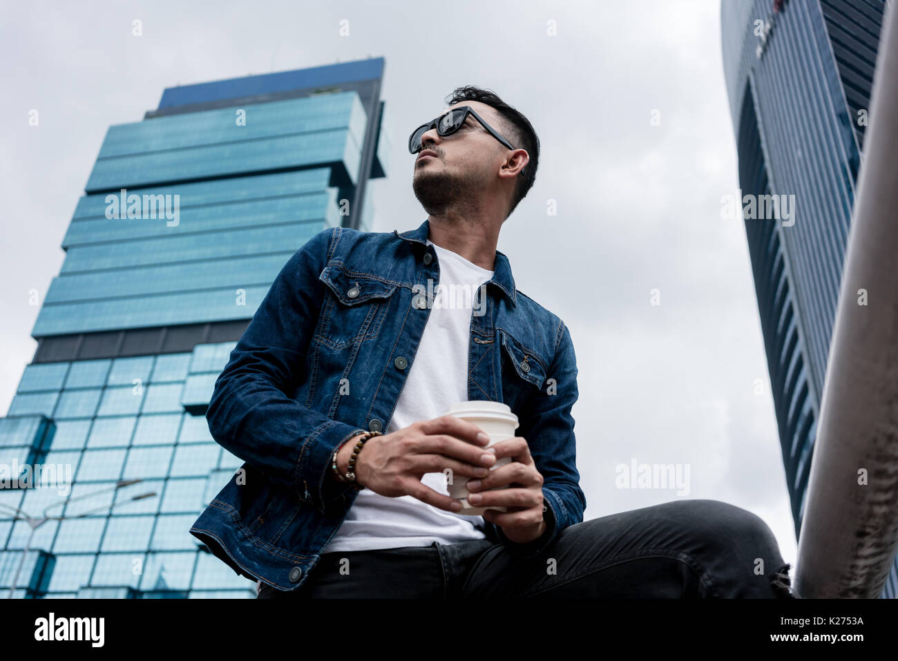 Giovane uomo che indossa blu denim camicia mentre fantasticando all'aperto ho Foto Stock
