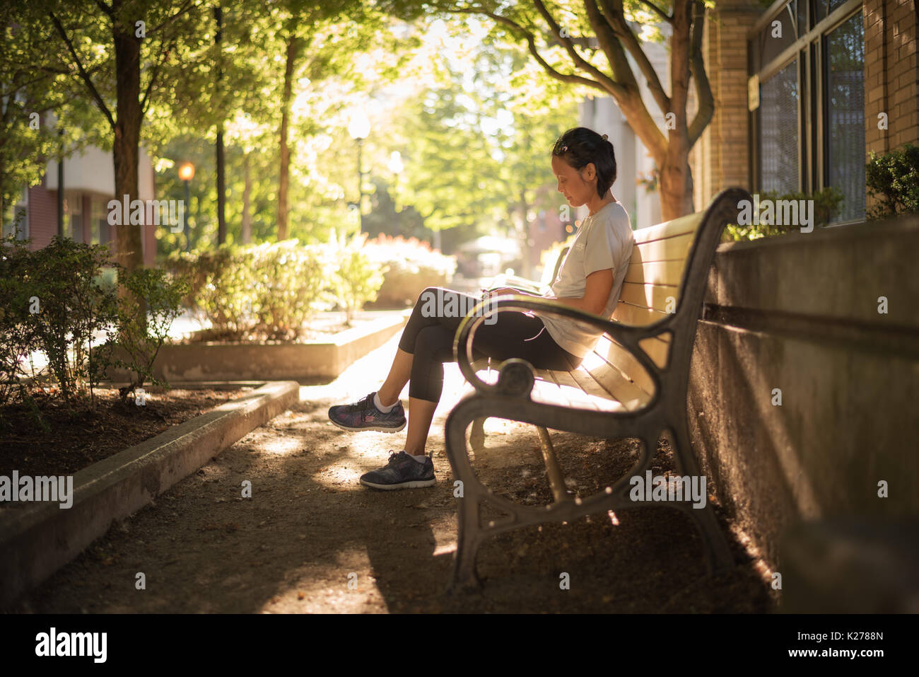 Una donna seduta su una città una panchina nel parco. Foto Stock