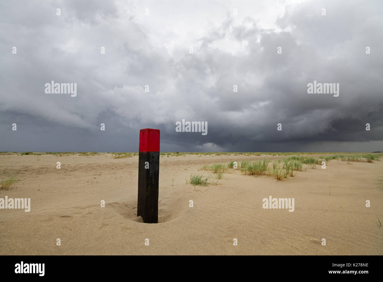 Polo di spiaggia su vasta spiaggia, nubi minacciose sopra il livello del mare Foto Stock