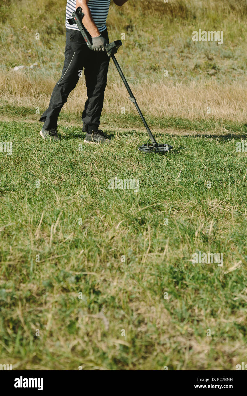 Persona di raccolto a camminare in campo nero con il rivelatore di metalli e la ricerca di oggetti preziosi. Foto Stock
