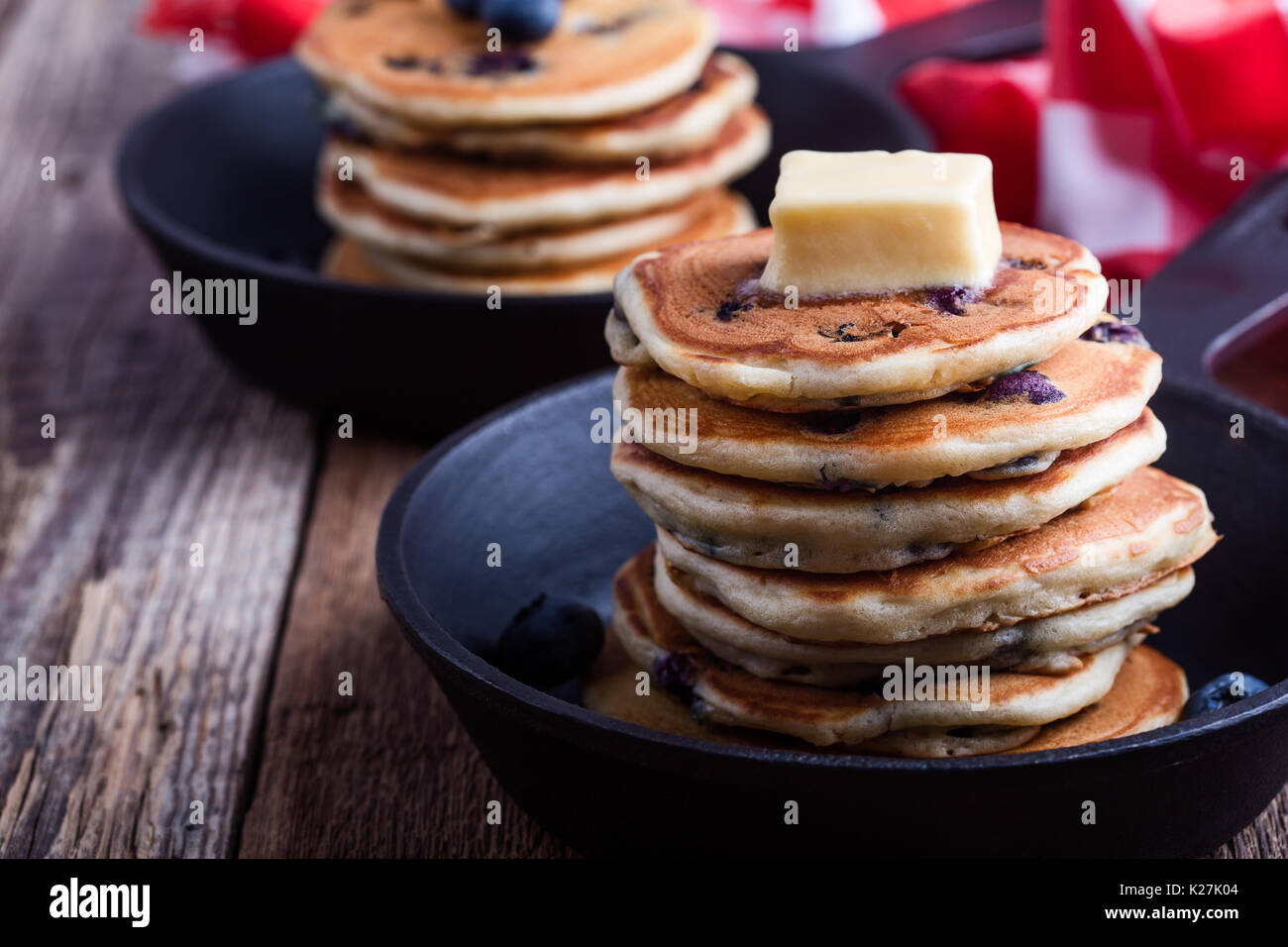 Pancake con mirtilli freschi conditi con il burro in padella in ghisa è servita per il brunch romantica sul tavolo rustico Foto Stock