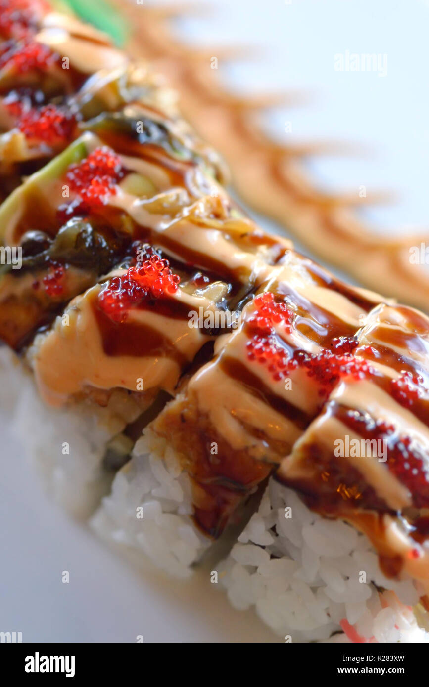 Primo piano artistico di drago rosso maki sushi roll con salmone e caviale Foto Stock