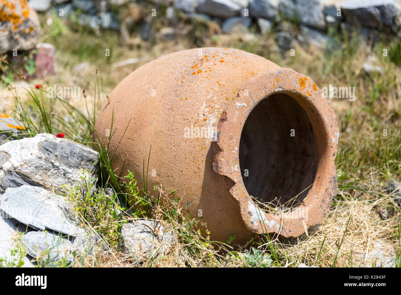 Un vecchio vaso in terracotta che giace sul suo lato tra le rovine archeologiche, di Delos, Grecia. Foto Stock