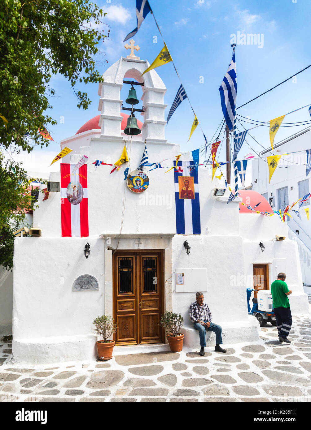 Piccola chiesa greco ortodossa con bunting e bandiere sul display, Mykonos, Greerce. Foto Stock
