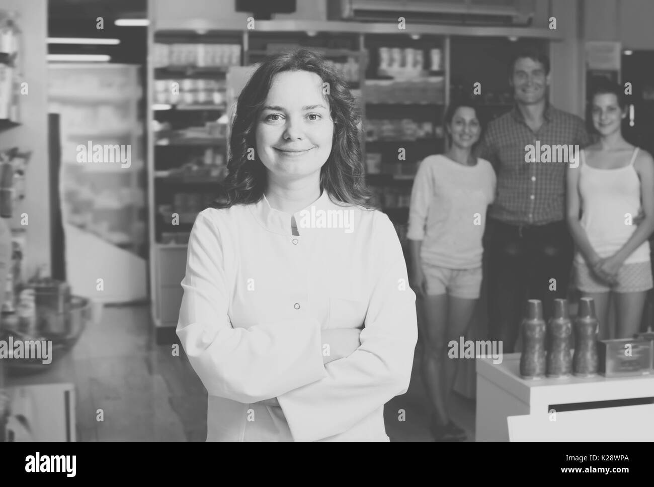 Donna felice il farmacista indossa mantello bianco si erge tra i ripiani in farmacia Foto Stock