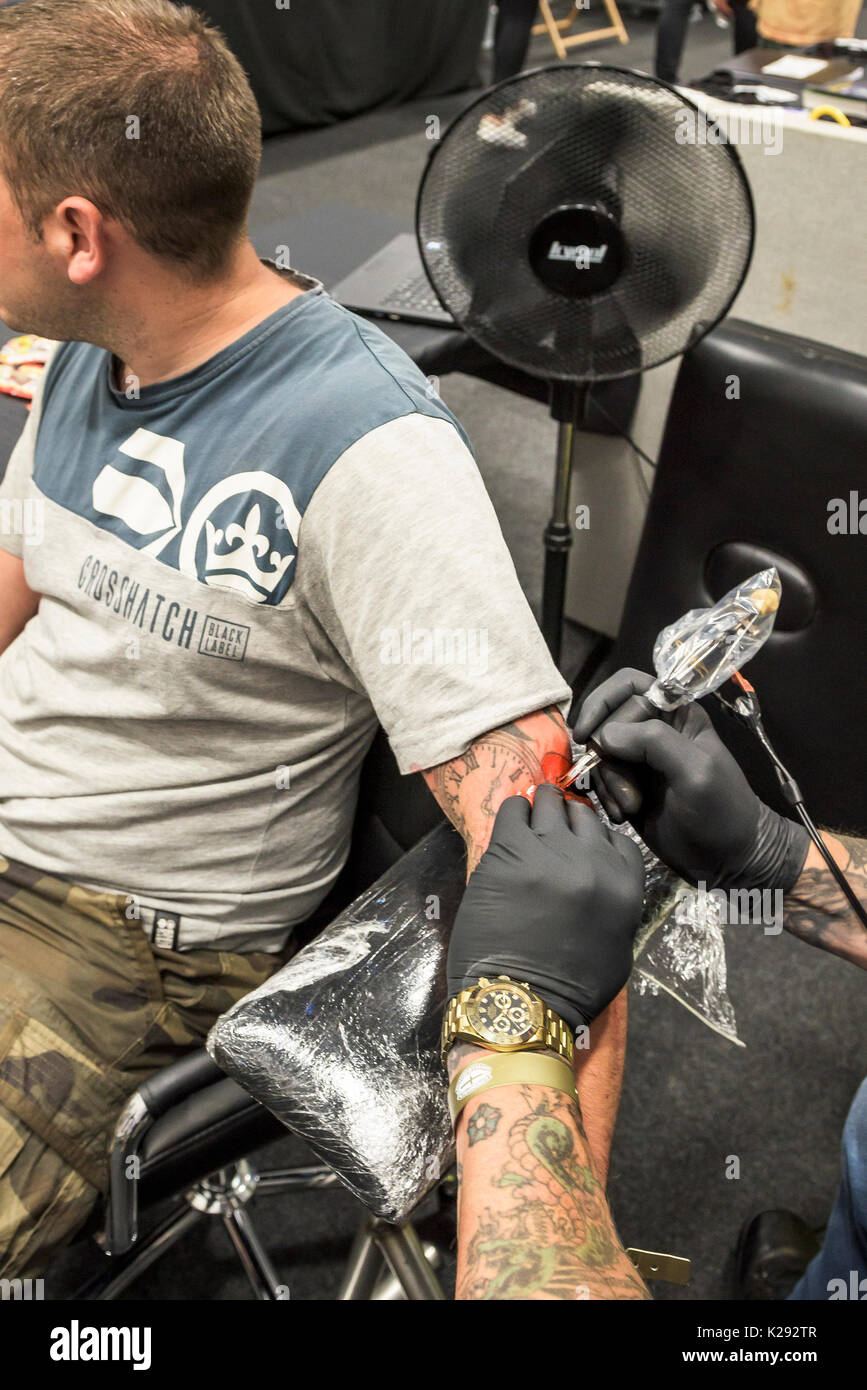 Cornwall Tattoo Convention - un tatuista che tatuava il braccio di un cliente alla Cornwall Tattoo Convention. Foto Stock