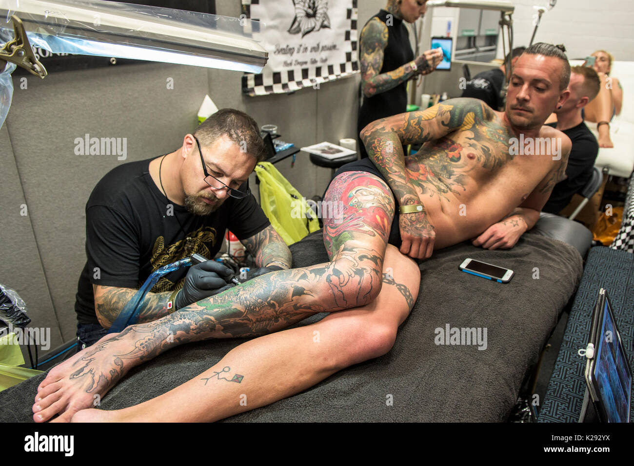 Cornovaglia Tattoo Convention - Luca Botterill tatuaggio un disegno sulla gamba di un cliente al Cornwall Tattoo Convention. Foto Stock