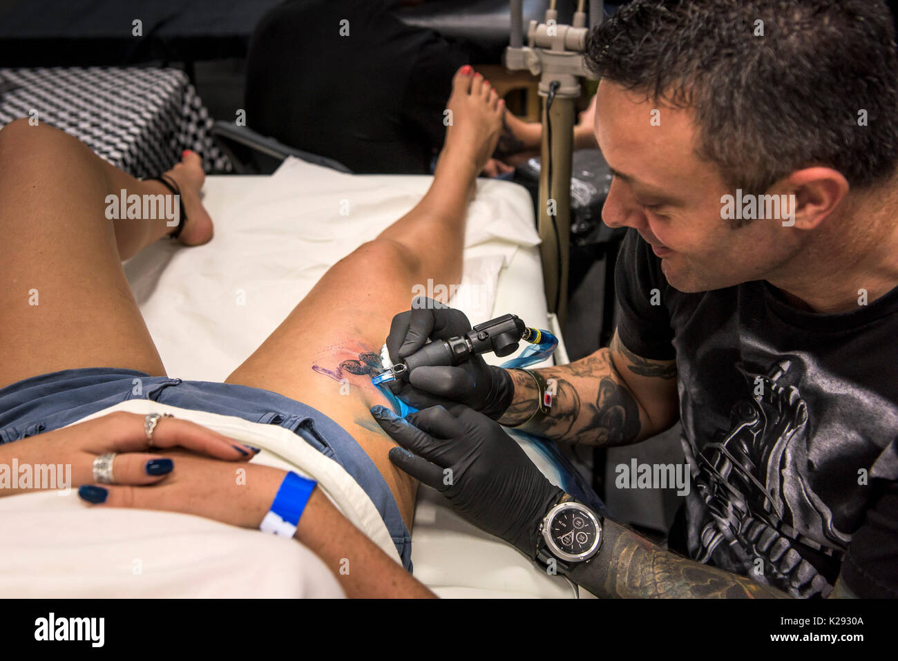 Tattoo - Mark razza tatuaggio un disegno sulla coscia di una femmina di cliente al Cornwall Tattoo Convention. Foto Stock