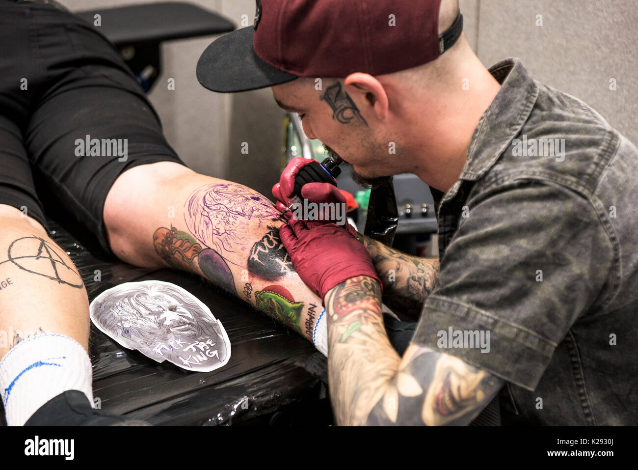 Cornovaglia Tattoo Convention - una vista ingrandita di Josh Docksey tatuaggio la gamba di un cliente al Cornwall Tattoo Convention. Foto Stock