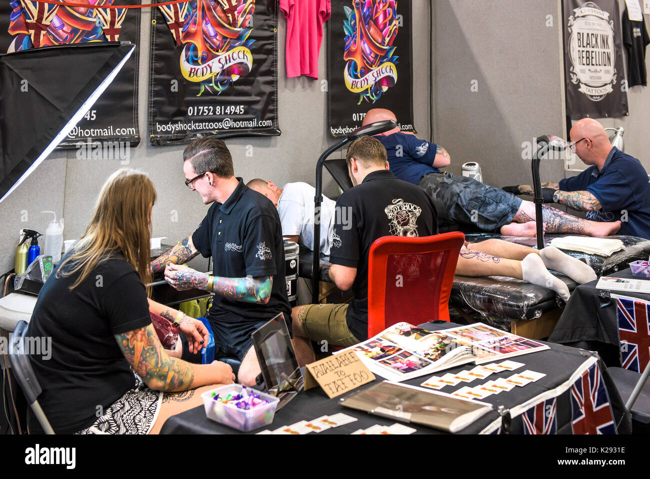 Cornovaglia Tattoo Convention - Tattooists lavorando sui loro clienti presso la Cornovaglia Tattoo Convention. Foto Stock