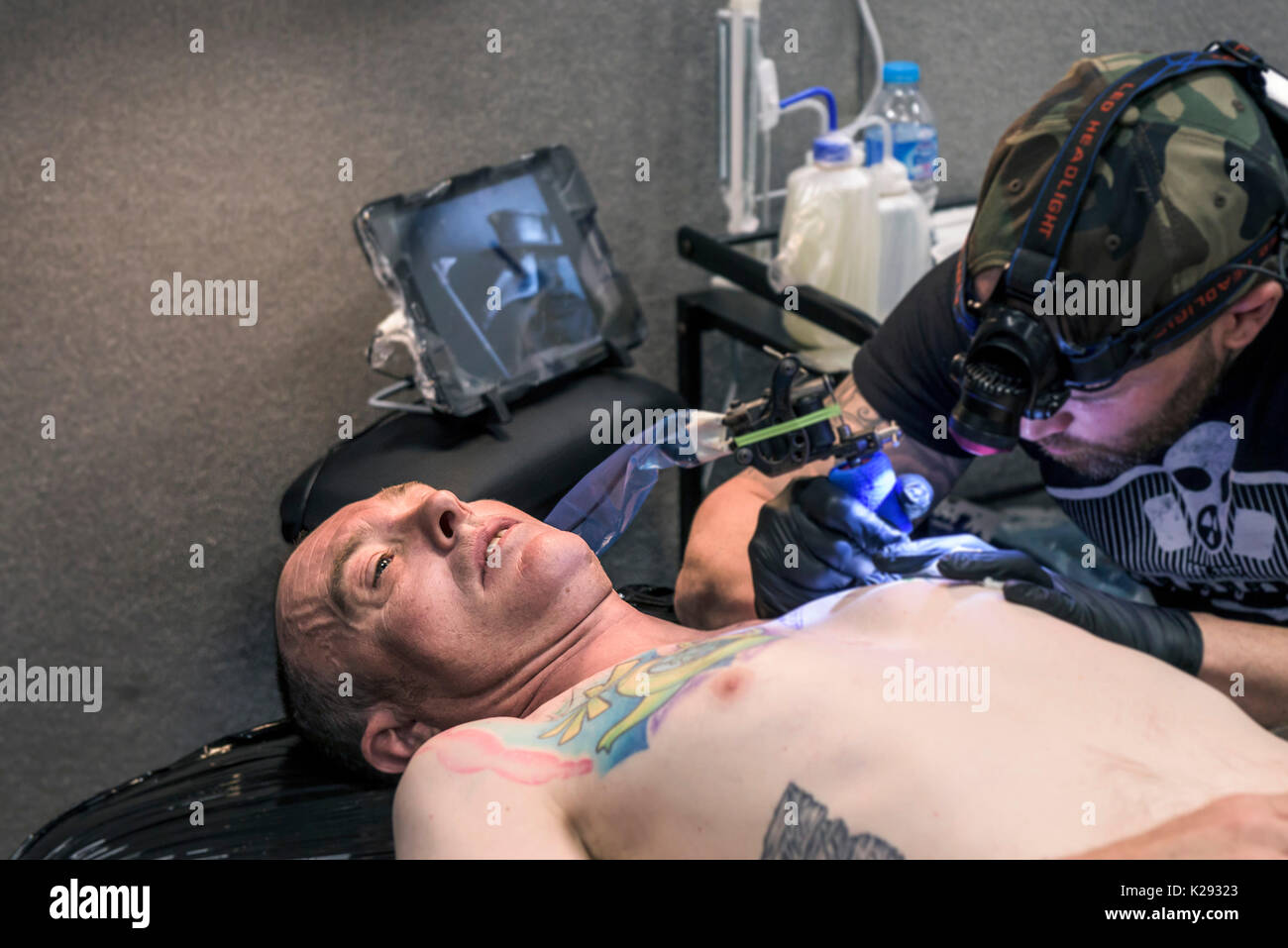 Cornovaglia Tattoo Convention - un cliente rilassante come il suo petto è tatuato in Cornovaglia Tattoo Convention. Foto Stock