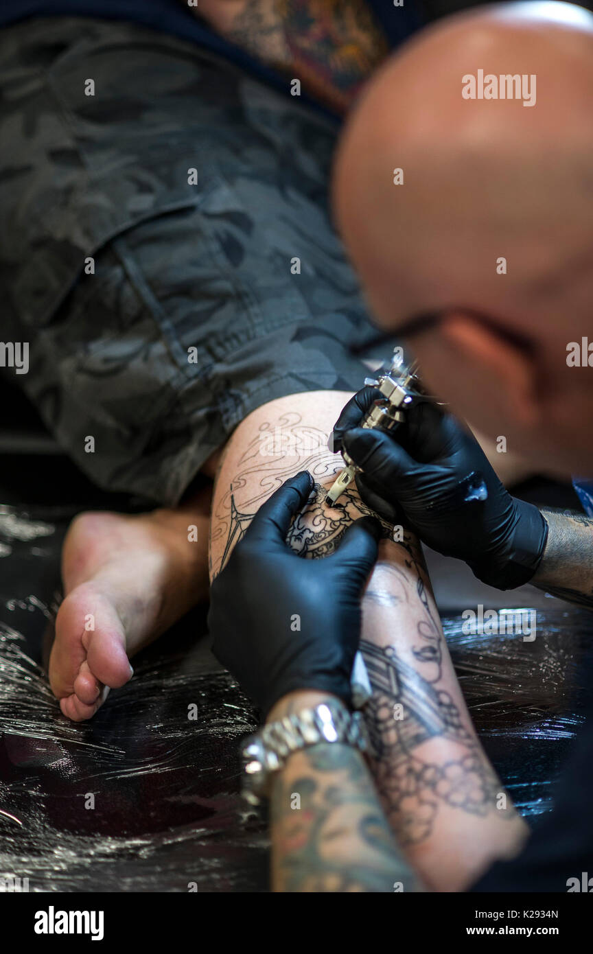 Cornovaglia Tattoo Convention - una vista ingrandita oftTattooist Andy Middleton tatuaggio la gamba di un cliente al Cornwall Tattoo Convention. Foto Stock