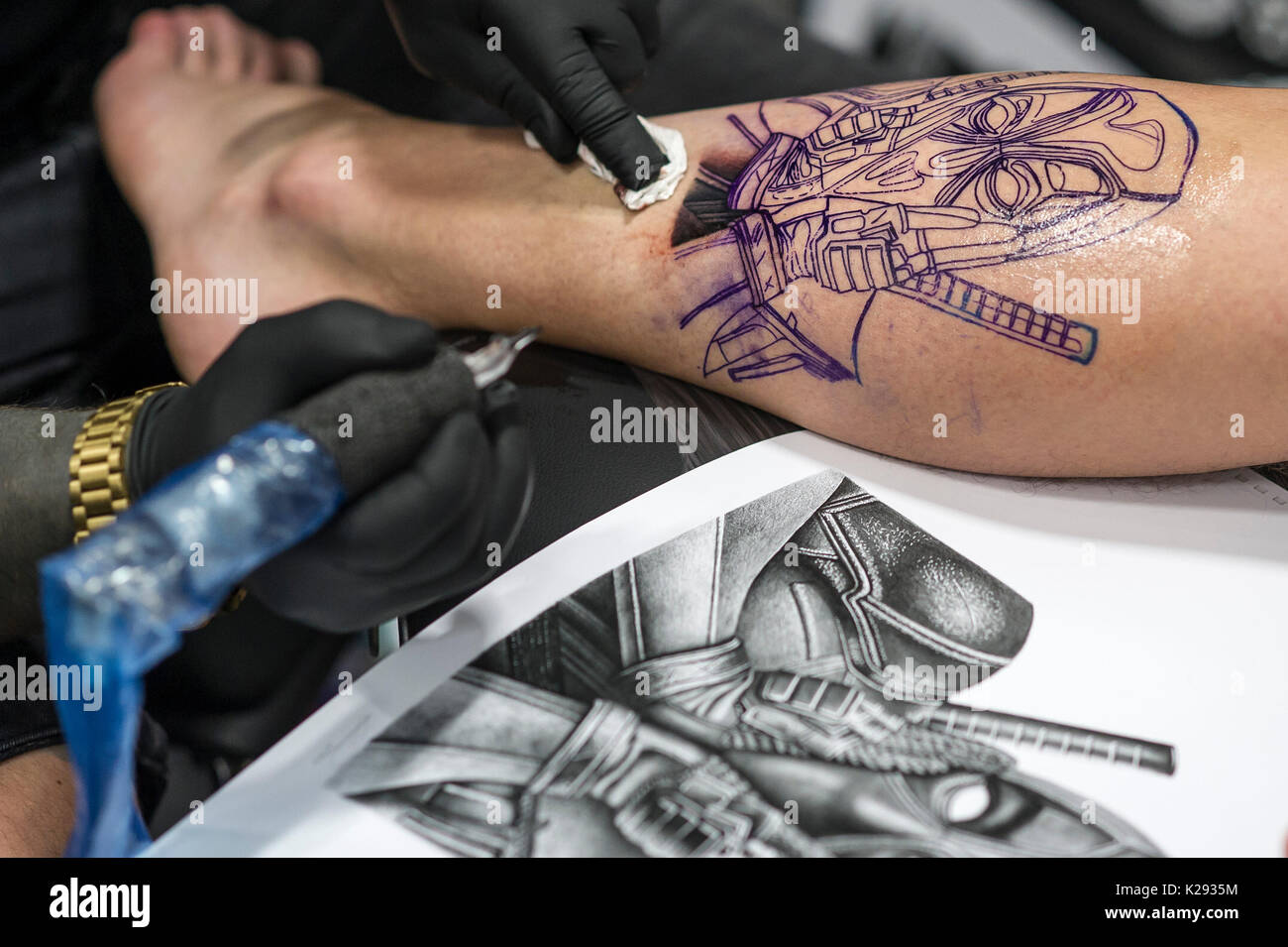 Tatuaggio. Un design essendo tatuato sulla gamba di un cliente al Cornwall Tattoo Convention. Foto Stock