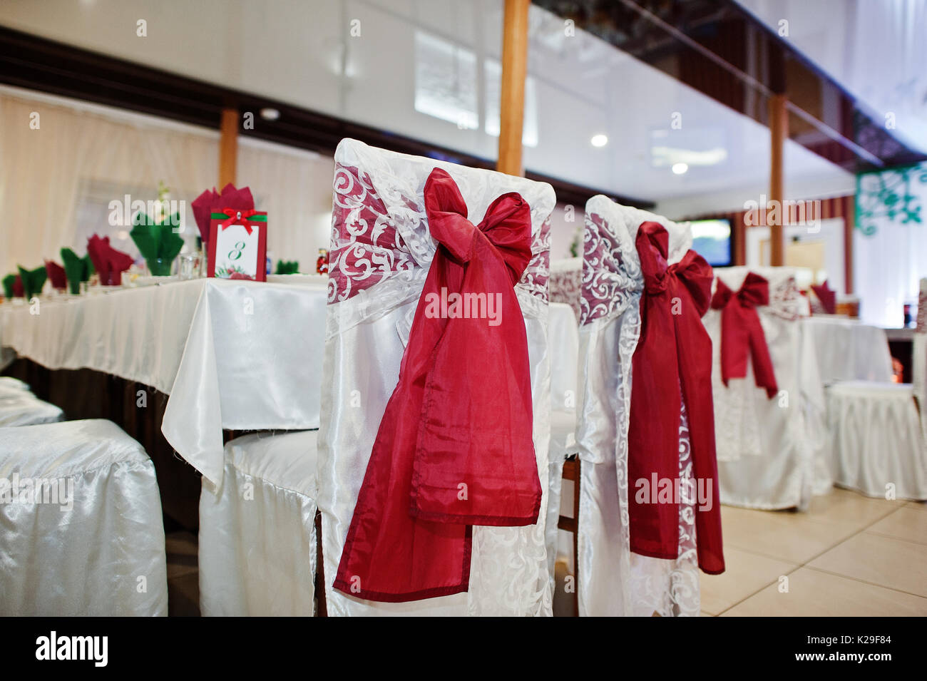 Sedie di nozze con centine rosso legato su di essi nel ristorante. Foto Stock