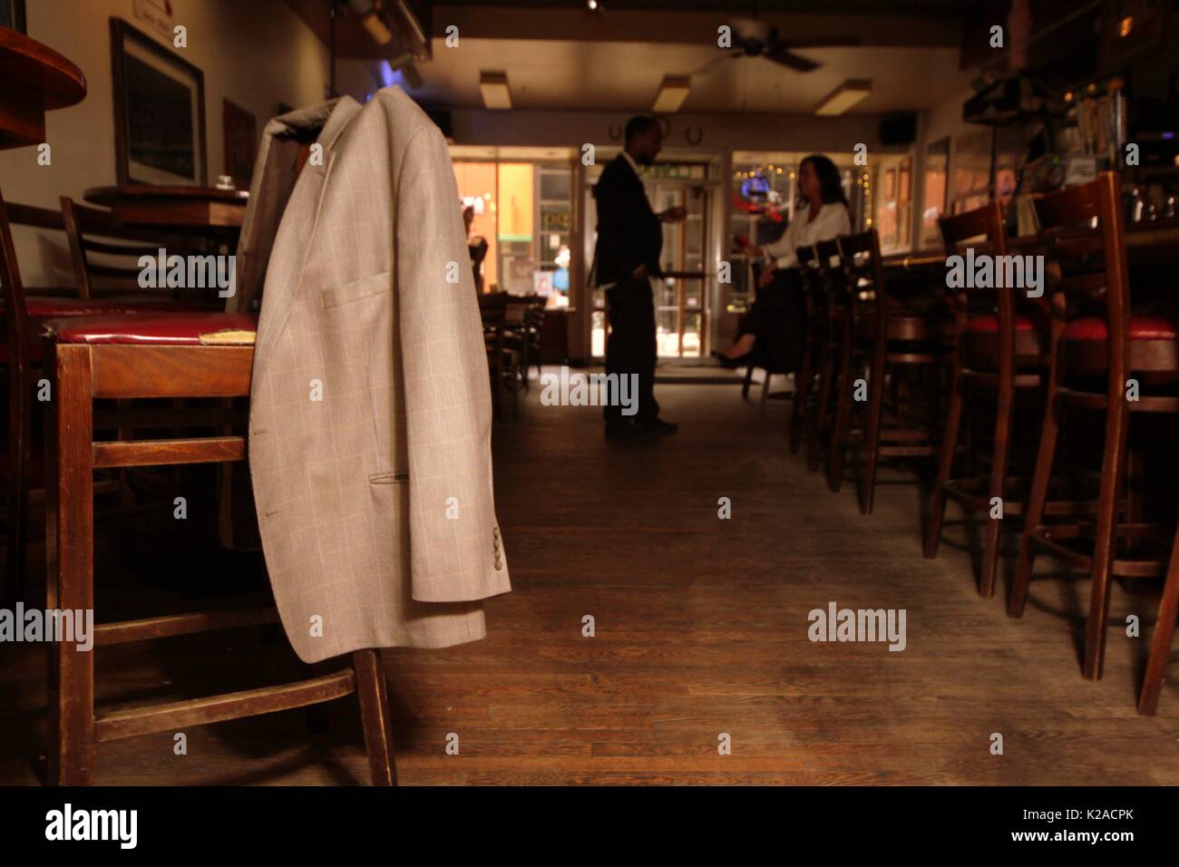 Giacca tuta appeso sul retro di un bar sedia (come se lasciato dietro) Foto Stock