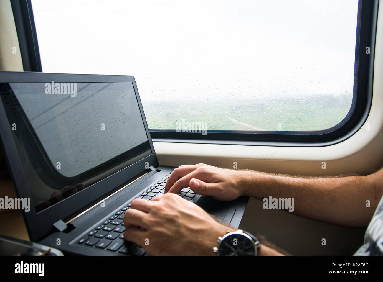 Uomo al lavoro su computer portatile in un treno Foto Stock
