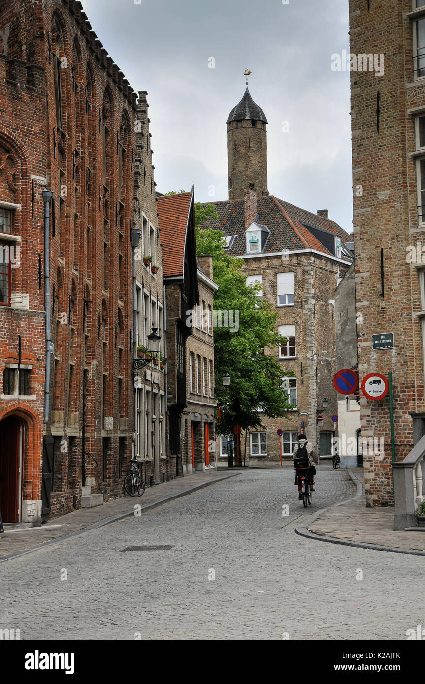 Un ciclista scorre verso il basso una tranquilla stradina secondaria nella città medievale di Brugge / bruges nelle Fiandre occidentali, Belgio Foto Stock