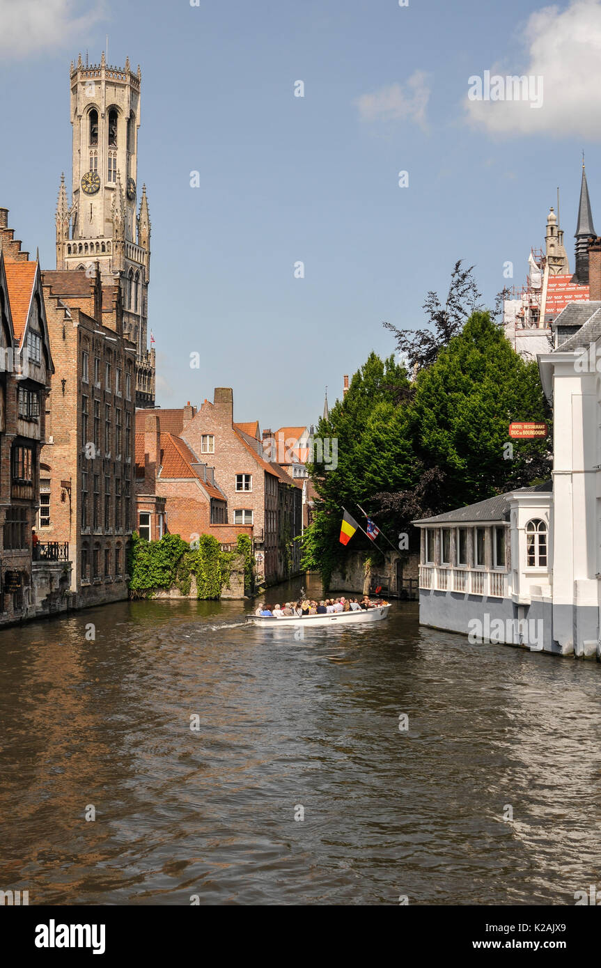 Lo skyline della città medievale di Bruges / bruges nelle Fiandre occidentali, in Belgio con l'acqua di un canale e l'imponente torre campanaria in piazza del mercato Foto Stock
