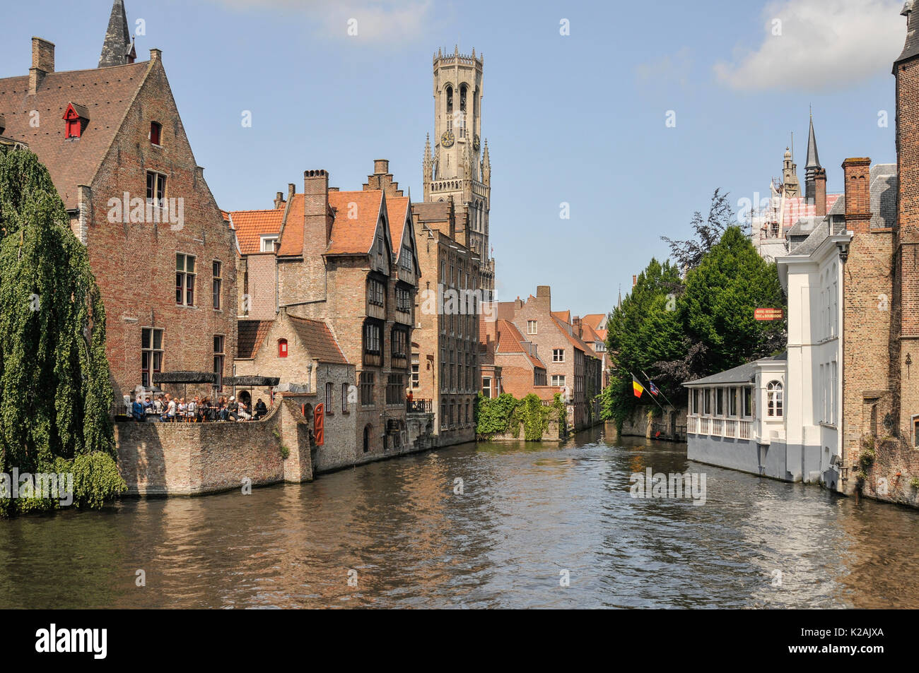 Lo skyline della città medievale di Bruges / bruges nelle Fiandre occidentali, in Belgio con l'acqua di un canale e l'imponente torre campanaria in piazza del mercato Foto Stock