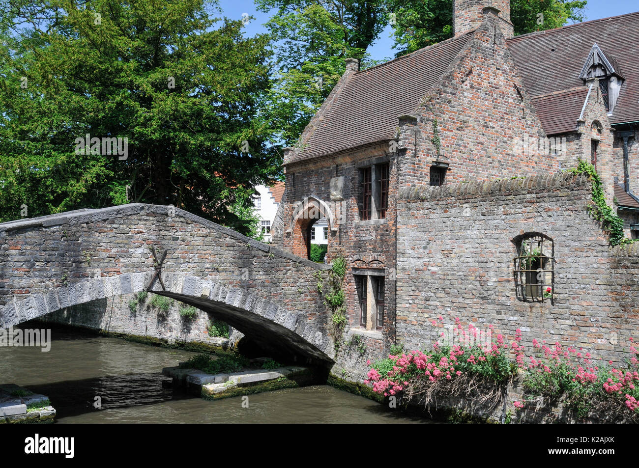 Passerella di piccole dimensioni su un tranquillo canale vicino ai musei della città medievale di Bruges / Bruges in una soleggiata giornata estiva Foto Stock