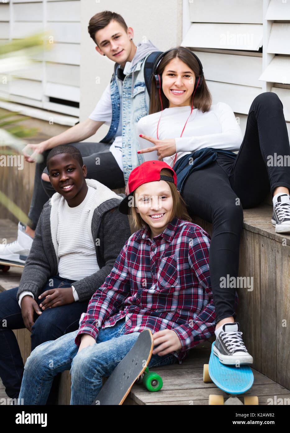 Felice ragazza e tre ragazzi appendere fuori all'aperto e discutere di un argomento Foto Stock