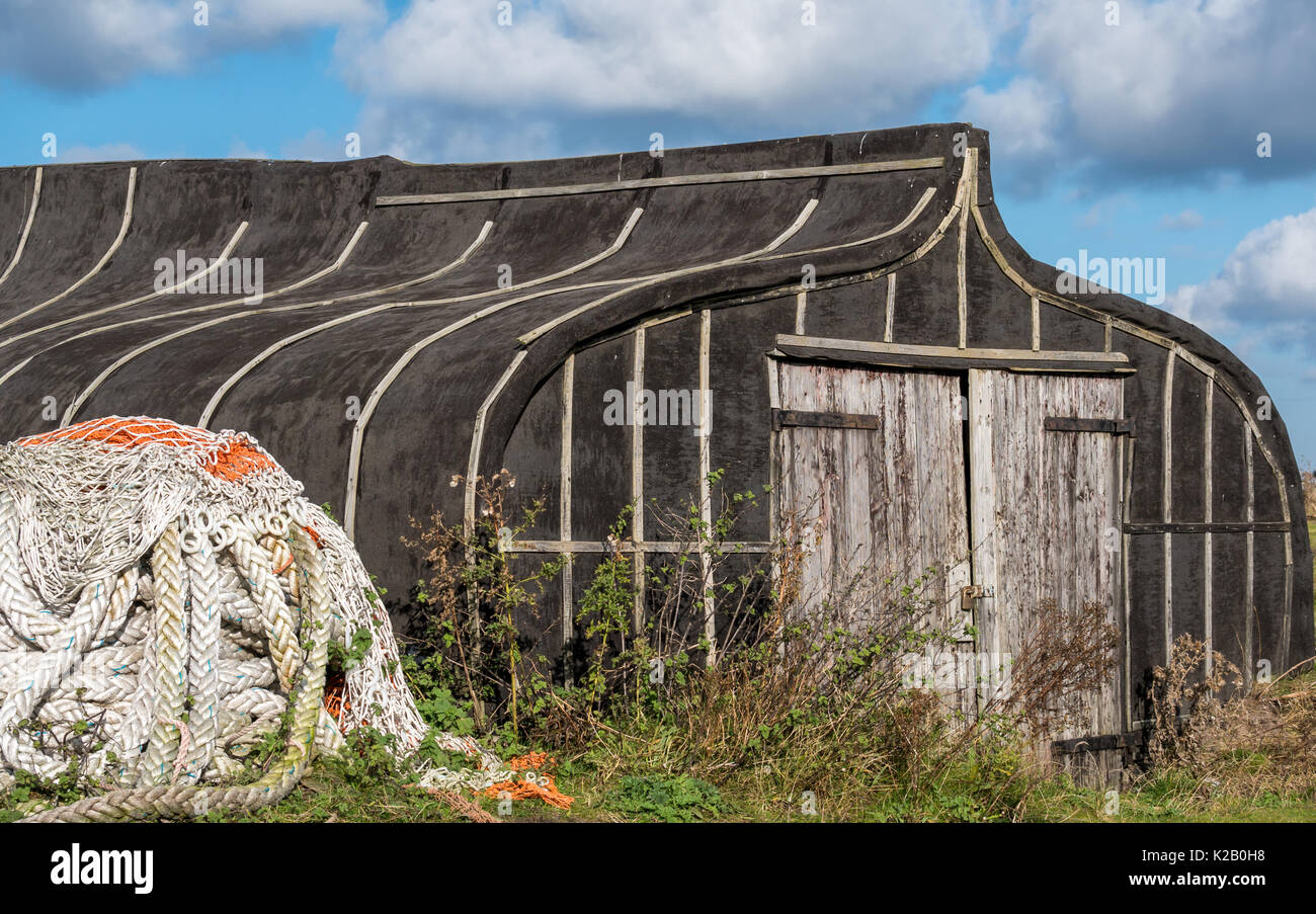 Barca capovolta, Isola Santa Lindisfarne, Northumberland, England, Regno Unito, ex aringhe nave della flotta, ora convertito in un capannone per il rimessaggio Foto Stock