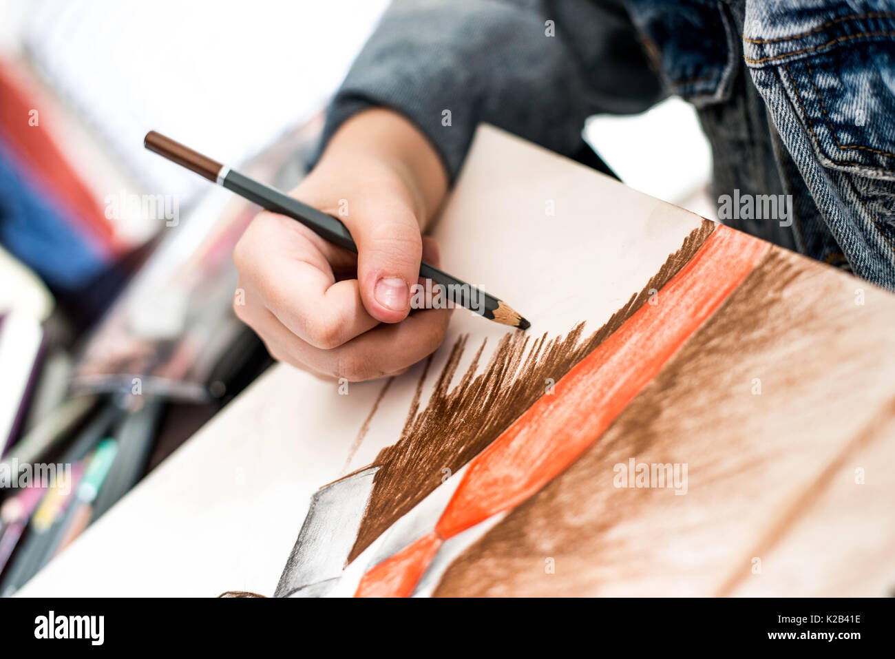 Persona di Disegno con matite su un tampone di arte che indossa una giacca di denim Foto Stock