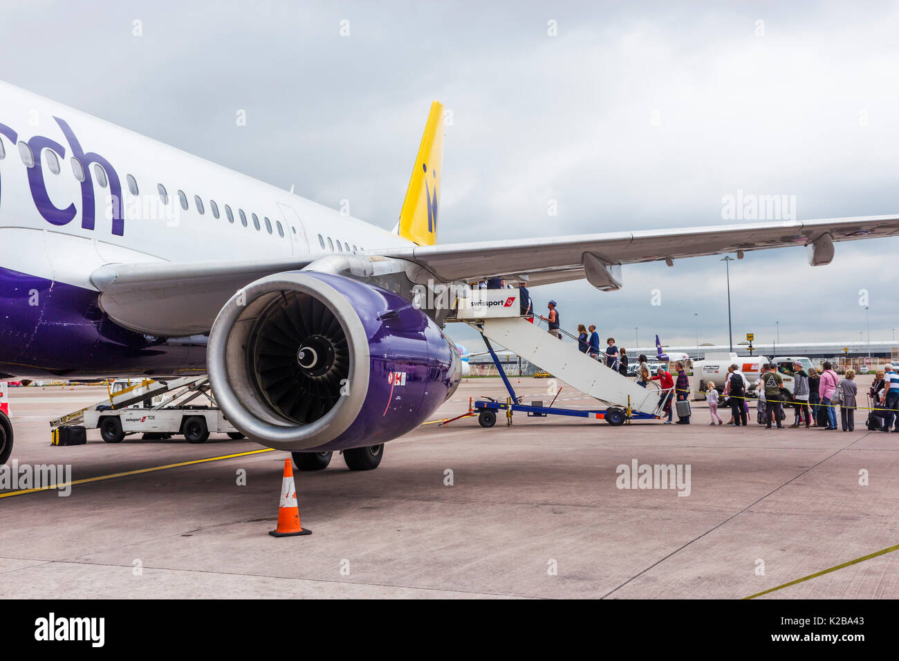 I passeggeri di salire a bordo di un Monarch Airlines voli in partenza per la Spagna da nuvoloso Manchester. Foto Stock
