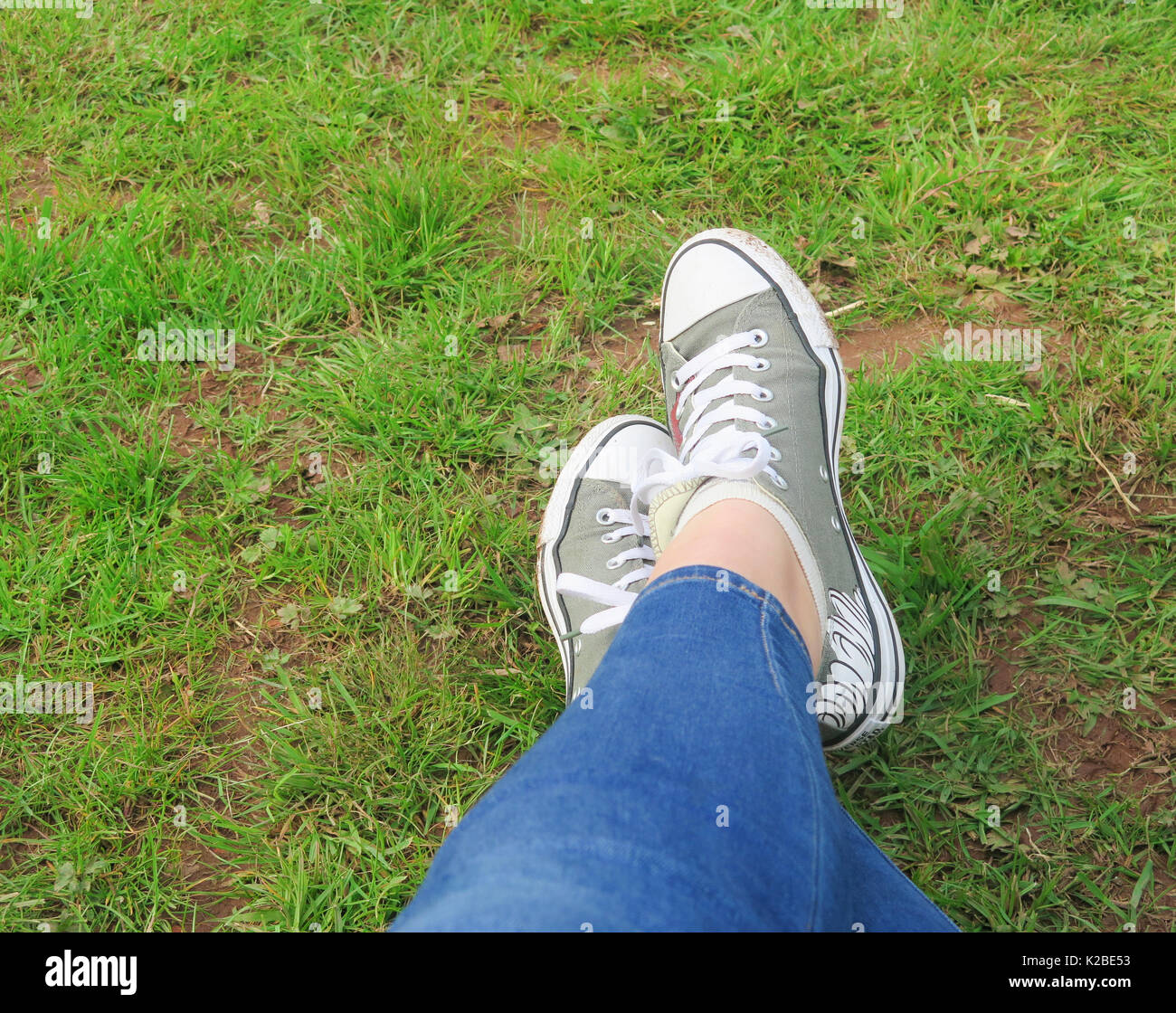 Ragazze incrociate le caviglie con Converse formatori Foto stock - Alamy