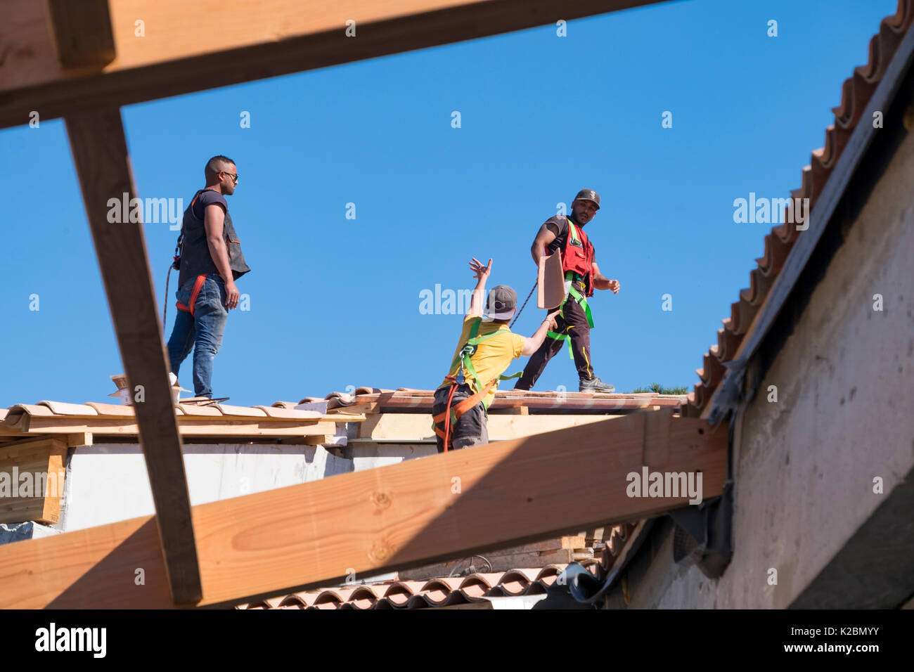 Conciatetti al lavoro installazione di piastrelle in una nuova casa in Provenza, Francia Foto Stock