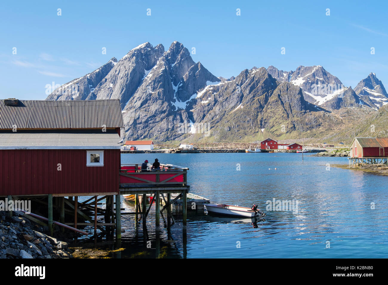 Stampen Cafe in rosso costruzione in legno su palafitte che si affaccia sul mare e sulle montagne nel villaggio di pescatori di Sund, Flakstadøya isola, isole Lofoten in Norvegia Foto Stock