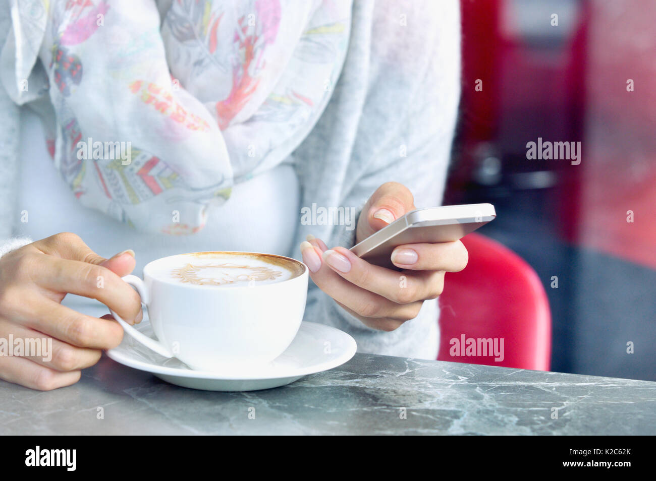 Vista ravvicinata della tazza di caffè e le mani di donne giovani con lo smartphone al cafe. Lo stile di vita e il concetto di tecnologia Foto Stock