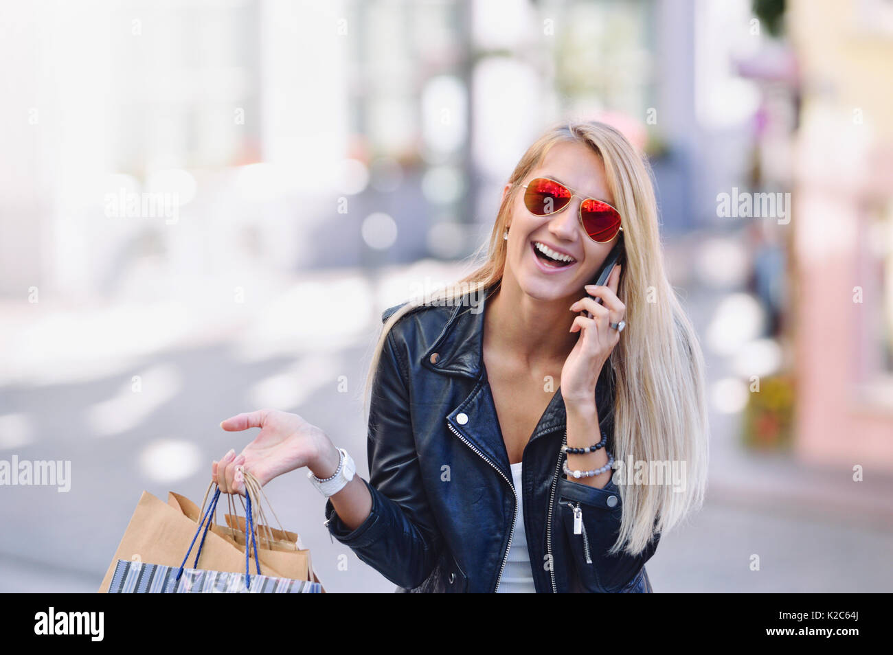 Giovane donna sorridente con shopping bags parlare dal telefono cellulare sul sottofondo stradale Foto Stock