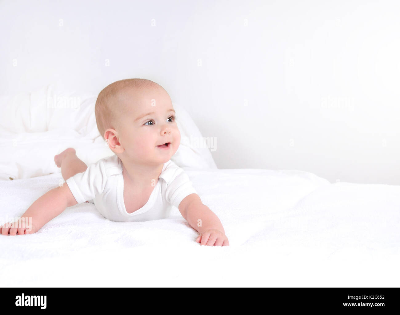 Neonato Bimbo giacente sorridenti su coltre bianca. carino neonato bianco su sfondo chiaro Foto Stock