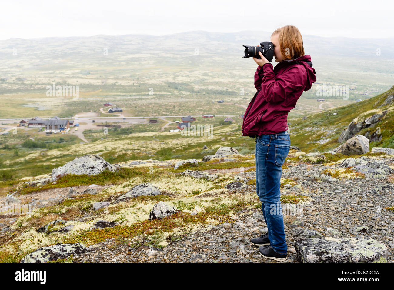 Giovani adulti donna caucasica prendendo fotografie del paesaggio di montagna su un nebbioso giorno d'estate. Foto Stock