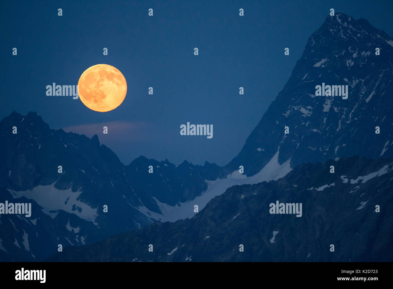 Full Moon Rising tra la Verpeilspitze (3430m, a sinistra) e l'Watzespitze (3554m, a destra). Questi picchi sono parte dell'Glockturmkamm, la cresta occidentale delle Alpi Otztal. Nordtirol, Alpi austriache. Luglio. Cucito digitalmente panorama. Foto Stock