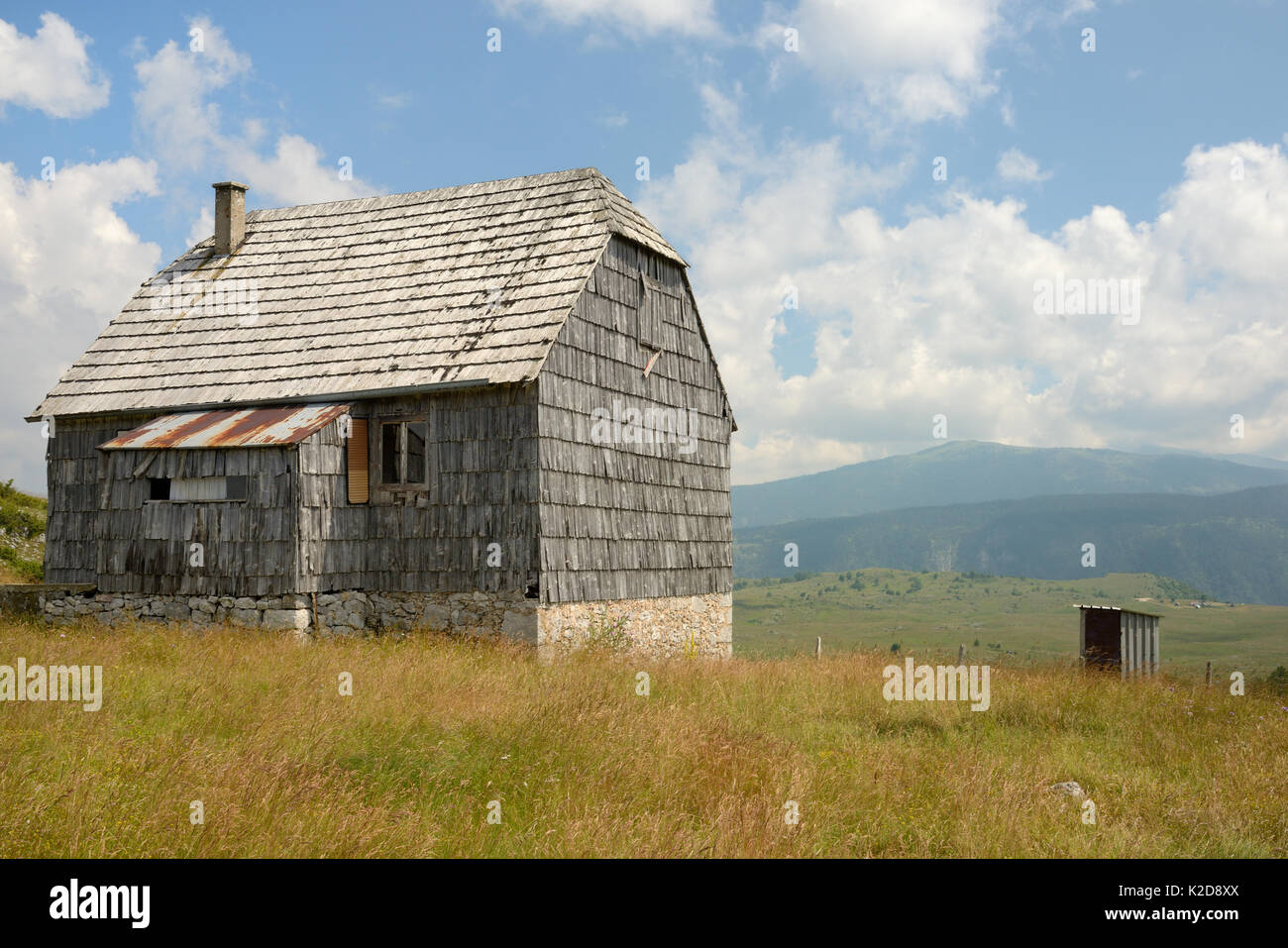 La vecchia casa colonica con pini ghiaia tetto e del mantello su Piva montagna altopiano (Pivska Planina) guardando verso il Parco Nazionale del Durmitor, Planina pianura, vicino Trsa, Montenegro, luglio 2014. Foto Stock