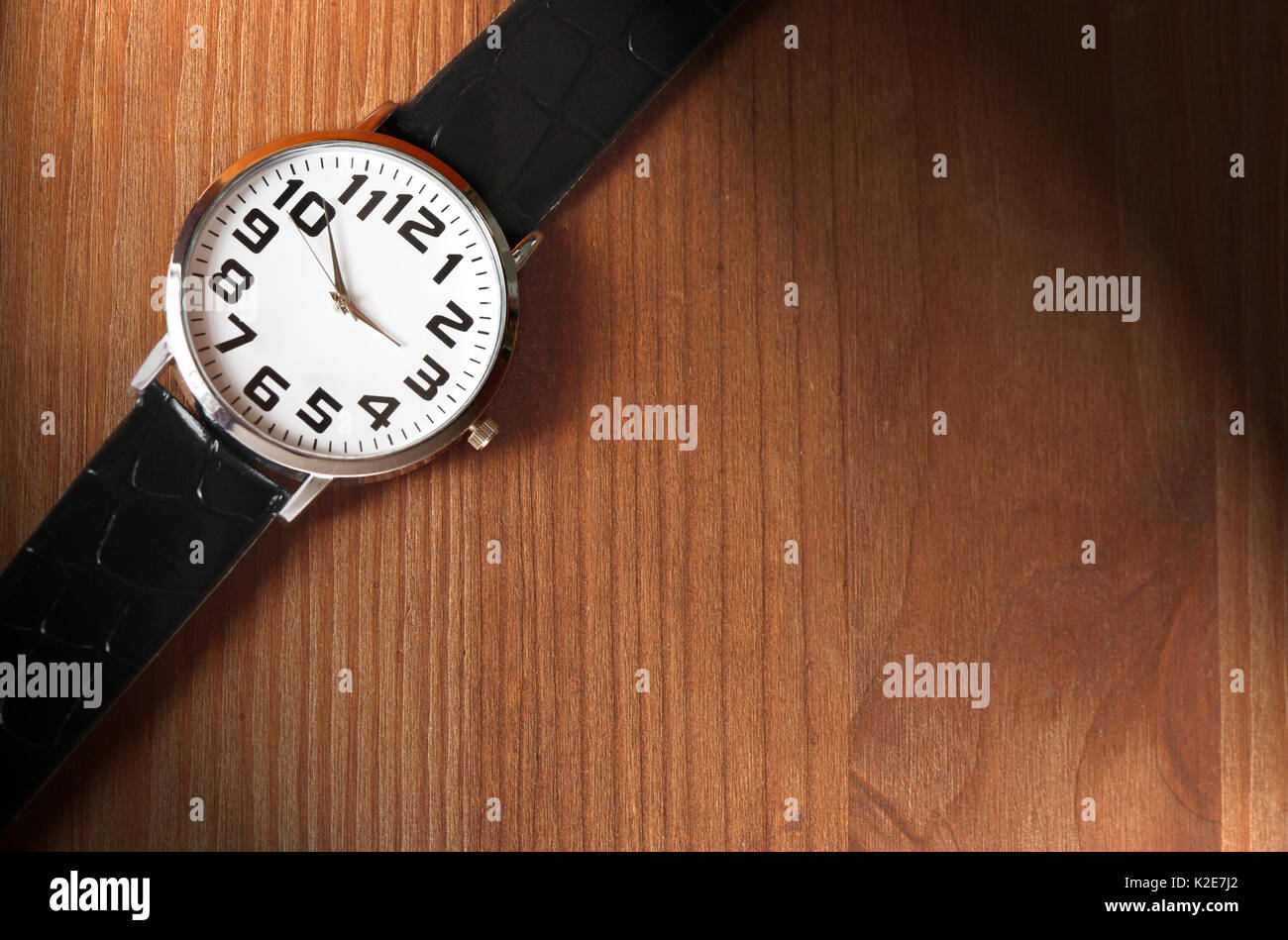 Orologio da polso moderni su una superficie di legno con effetto di illuminazione Foto Stock