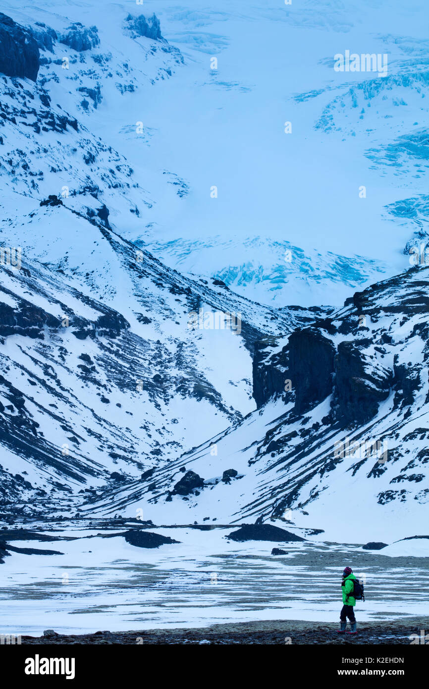 Donna che cammina sotto Skaftafell, sud dell'Islanda, Dicembre 2016 Foto Stock