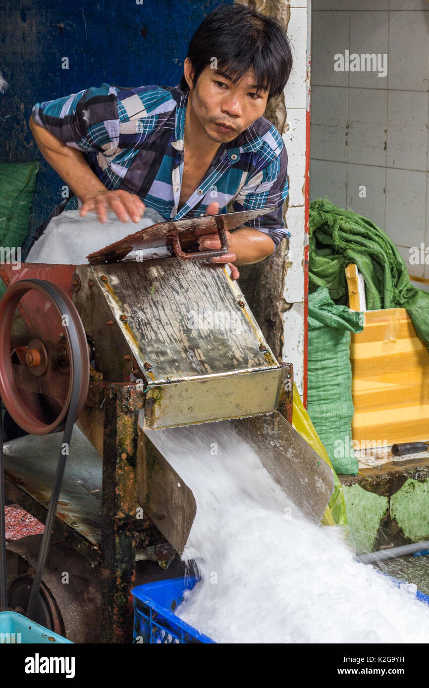 Uomo che utilizza la macchina a frantumare blocchi di ghiaccio, la città di Ho Chi Minh (Saigon), Vietnam Foto Stock