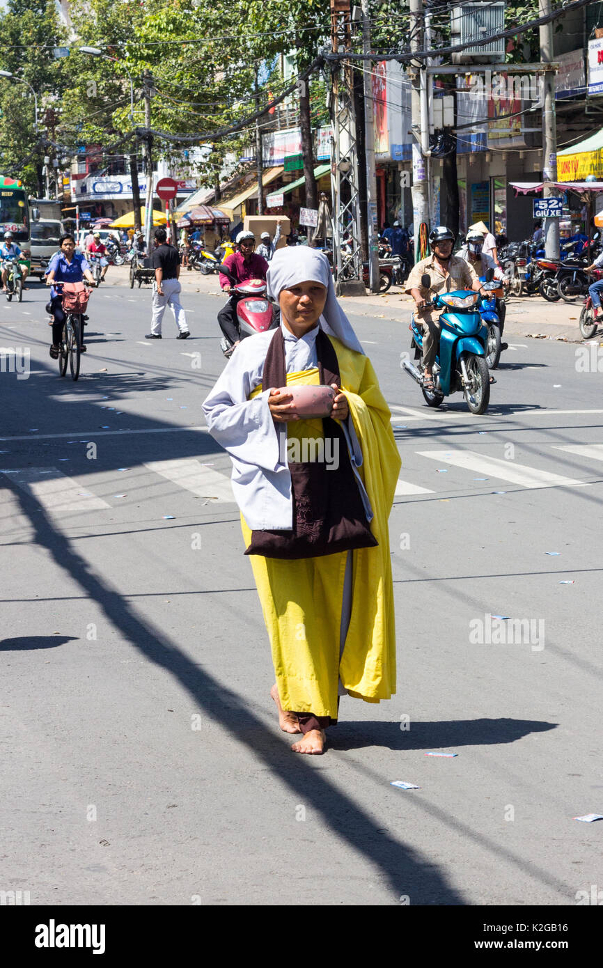 Nun camminando giù per una strada in Cholon raccogliendo elemosine, Città di Ho Chi Minh (Saigon), Vietnam Foto Stock