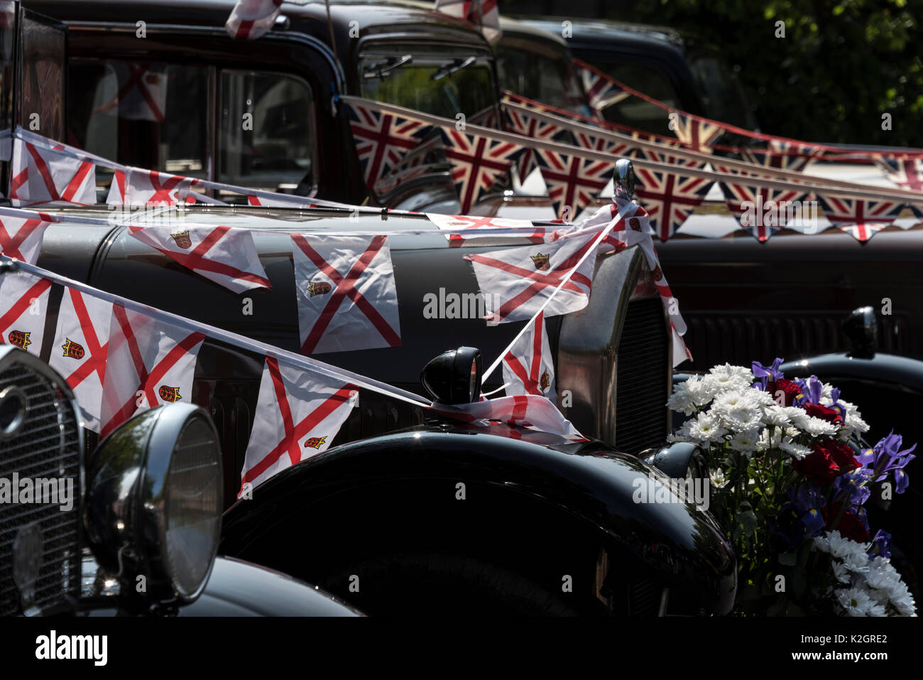 Una stringa di mini Jersey bandiere decorano i berretti di una fila di pre-1951 automobili classiche del Jersey Vecchio Motorino Club Ltd, presso il Jersey War Tunnels - Ge Foto Stock