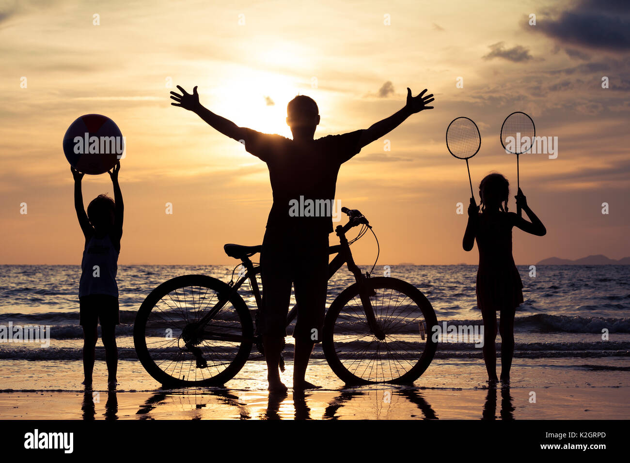 Padre e figli giocando sulla spiaggia al tramonto. Concetto di felice famiglia amichevole. Foto Stock