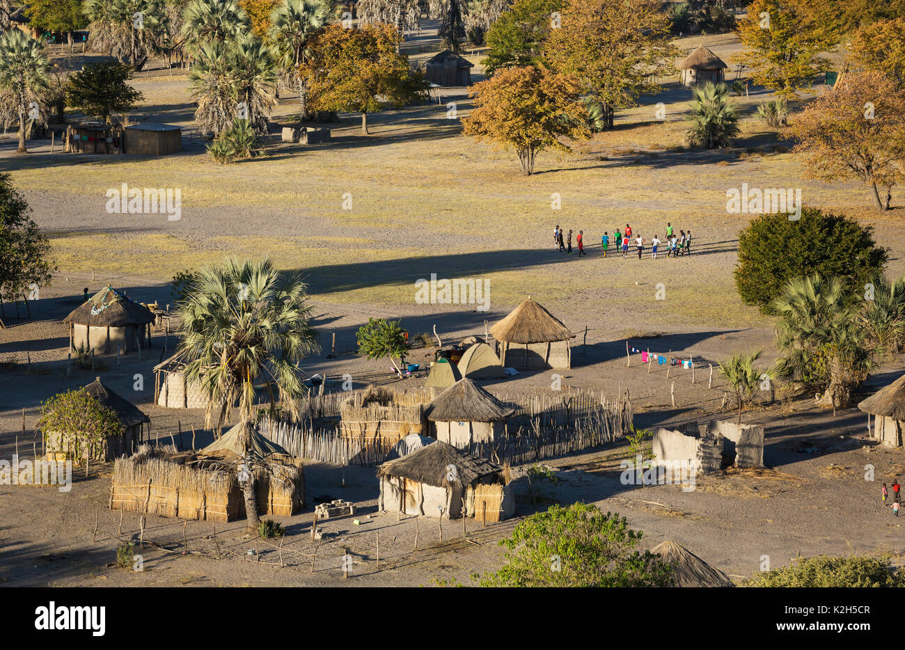 Villaggio nativo appena al di fuori della zona protetta, prominente di un gruppo di giovani uomini pronti per una partita di calcio, vista aerea, Okavango Delta, Botswana Foto Stock