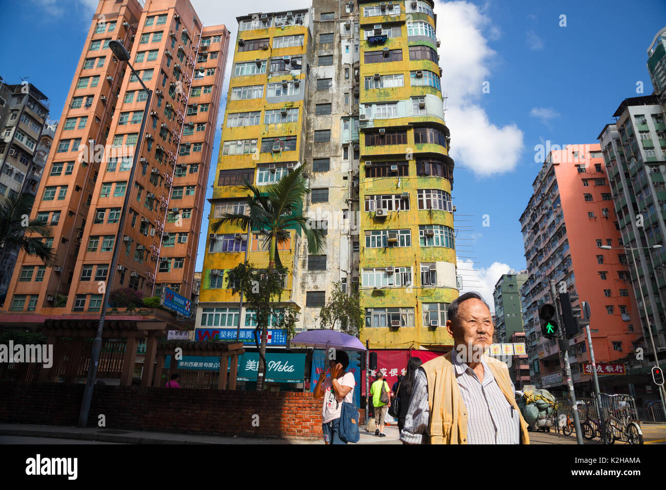 Un uomo cammina per le strade di Kowloon con edifici tipici, Hong Kong Foto Stock