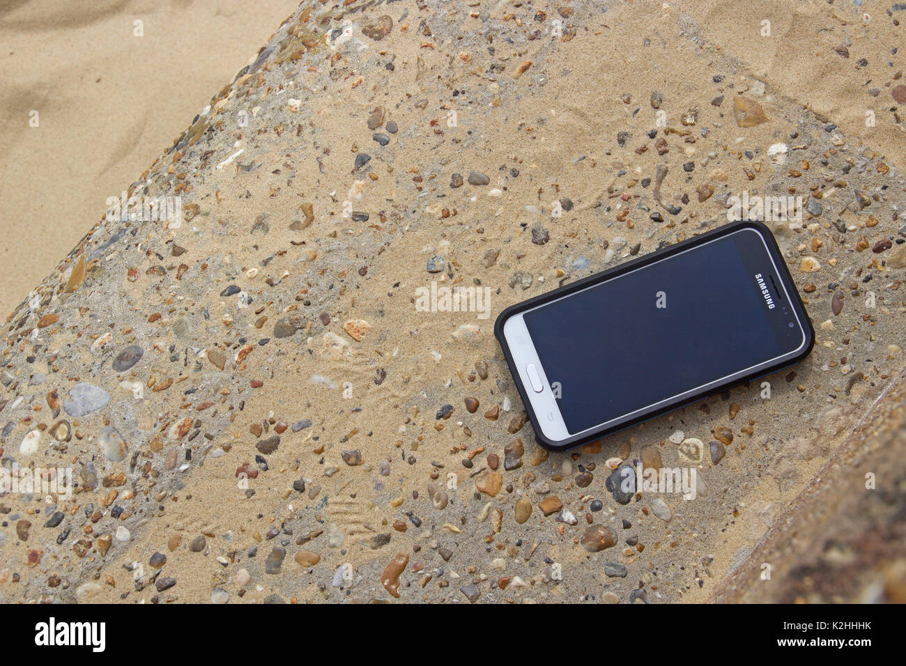 Un cellulare Samsung in una custodia di protezione su un muro di cemento Foto Stock