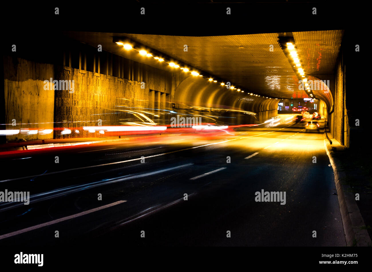 Il traffico di notte sulle strade della città. I veicoli di salire in e fuori del tunnel in motion blur Foto Stock